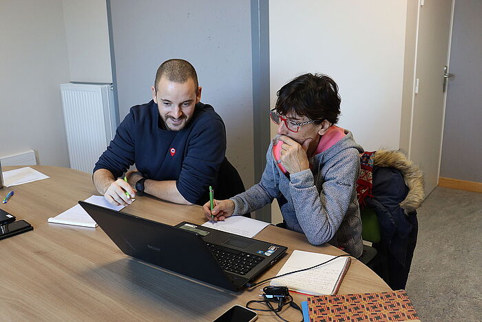 Romain accompagne une usagère sur son ordinateur